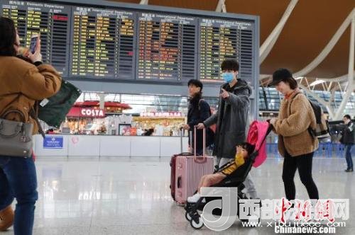 旅客帶著孩子前往辦票柜臺(tái)辦理登機(jī)手續(xù)?！∫罅⑶?攝
