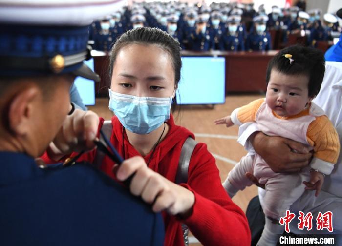 新消防員楊振的妻子彭莉與女兒現(xiàn)場見證丈夫加入“火焰藍”的神圣時刻?！⒅铱?攝