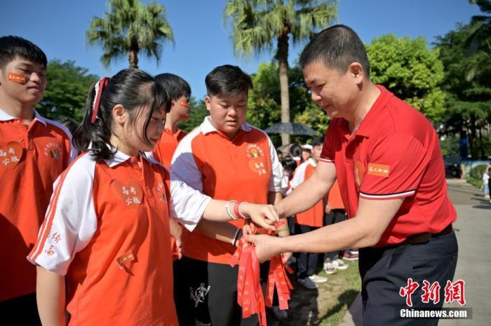 資料圖：廣西華僑實驗高中的教師為高三學(xué)子系上紅絲帶，盼望學(xué)子高考必勝。 俞靖 攝